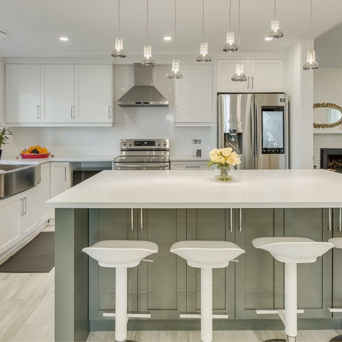 Modern kitchen with white cabinetry, green island, pendant lights, and stainless appliances in Greater Vancouver