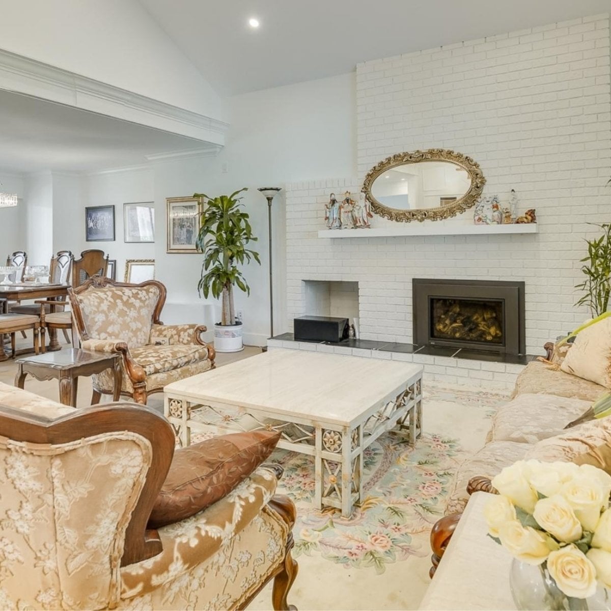 Traditional living room with a white brick fireplace, ornate furnishings, and floral accents in Greater Vancouver