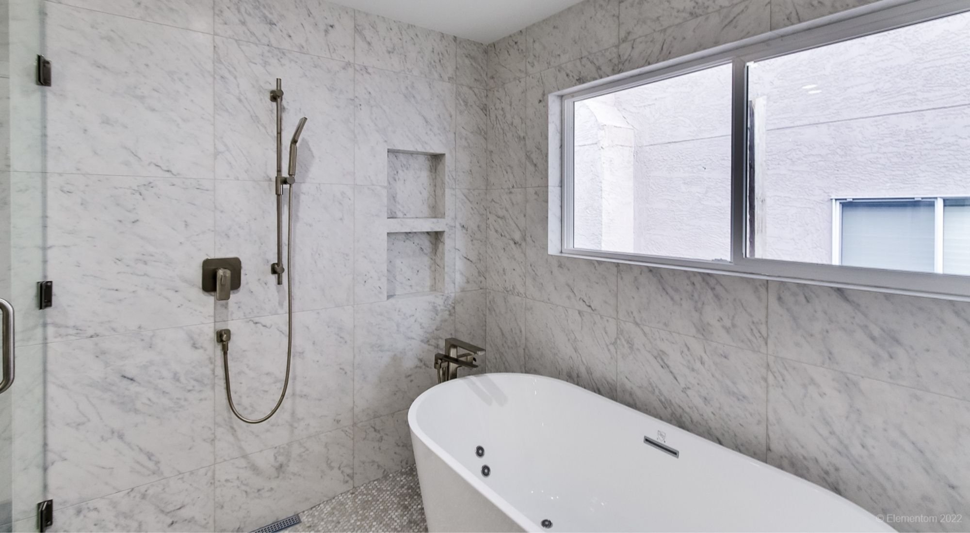 Bathroom with freestanding tub, marble tiled walls, built-in shower niches, and large window + Greater Vancouver - o
