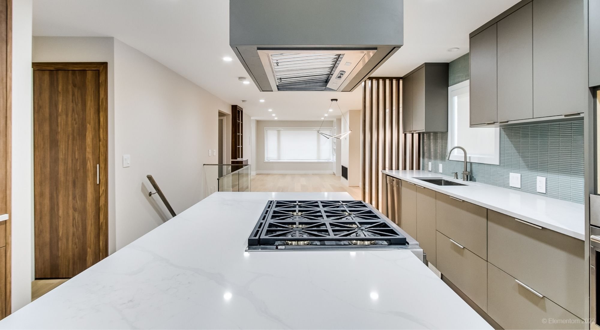 Kitchen island with gas cooktop, white stone countertop, gray cabinetry, and range hood + Greater Vancouver - optimi