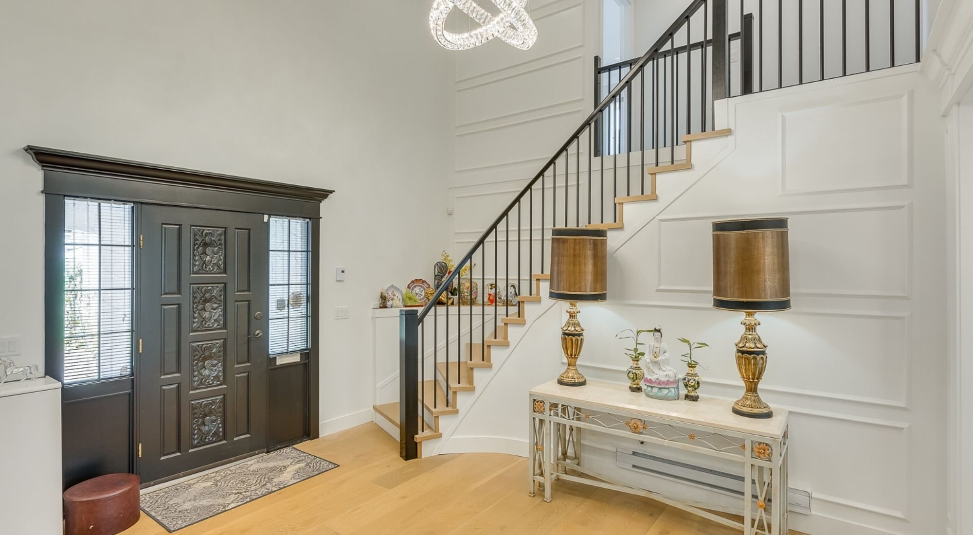 Renovated entryway with modern staircase, black railings, wood flooring, and paneled walls + Greater Vancouver - opt