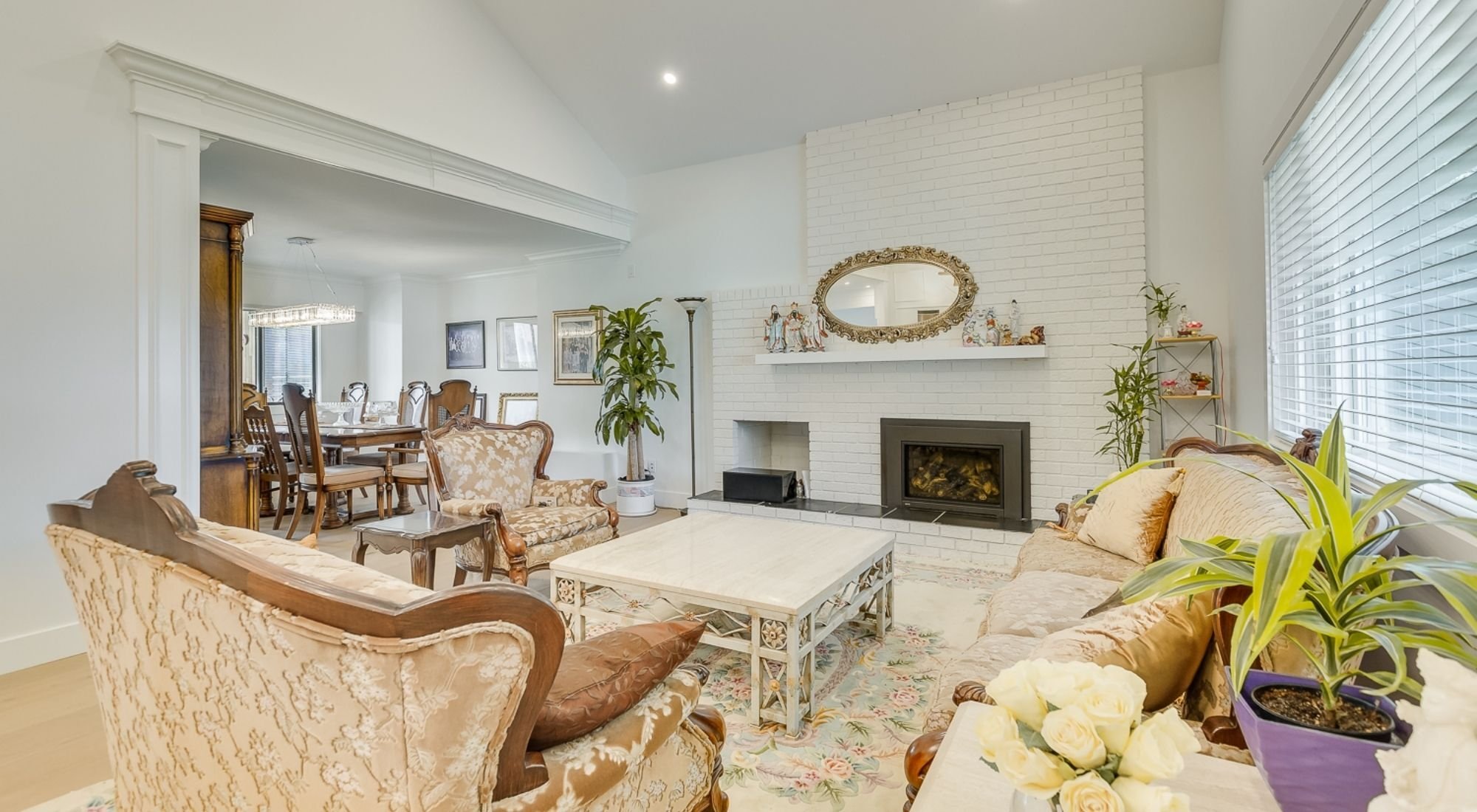 Renovated living room with white brick fireplace, open dining area, and bright modern finishes + Greater Vancouver -