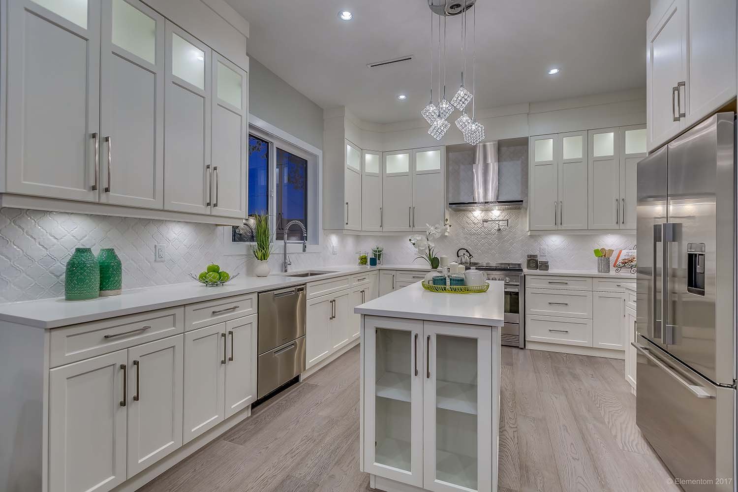Bright modern kitchen with white cabinetry, quartz countertops, centre island, stainless steel appliances, and pendant lights.