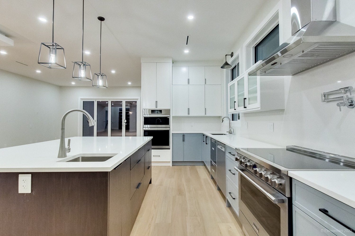 Bright white Vancouver kitchen with stainless steel range hood, dark wood island, and pot filler faucet