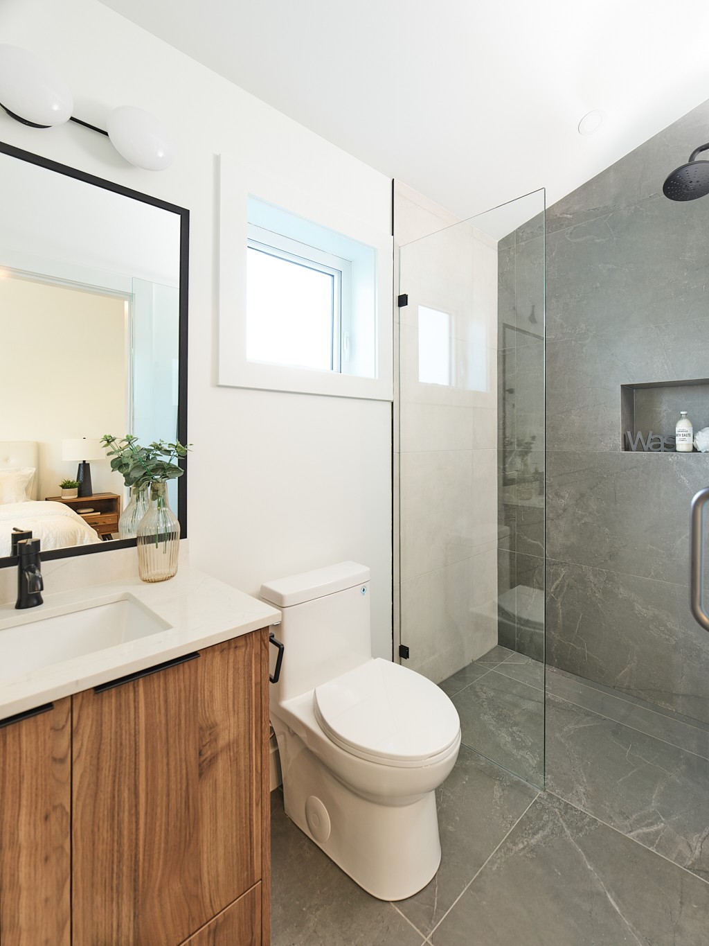 Vancouver bathroom with walk in glass shower, gray stone tile, and walnut vanity