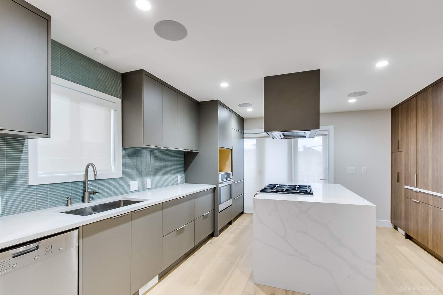 Sleek kitchen with marble island and wood floors.