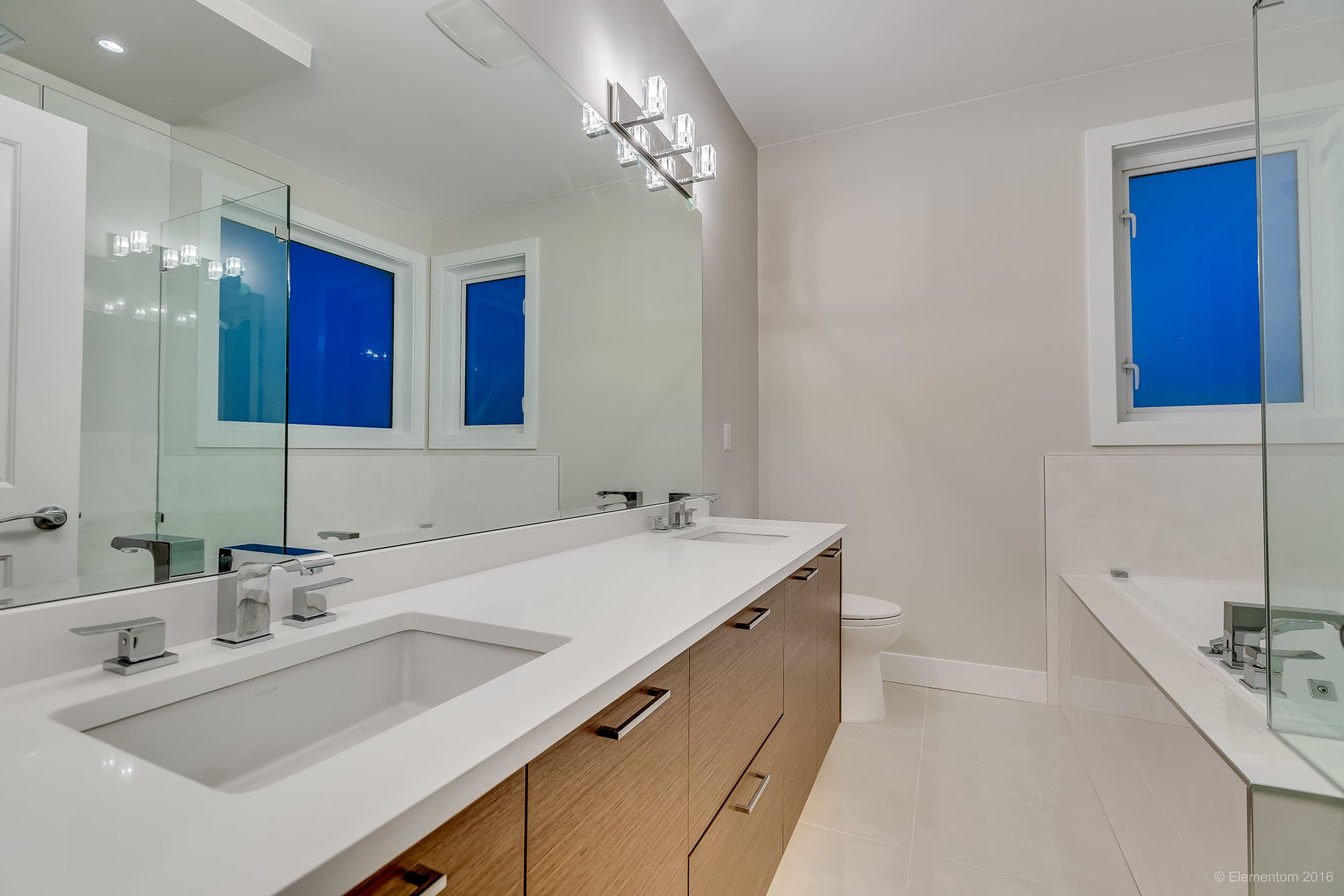 Modern bathroom with double vanity, large mirror, and glass shower in a Greater Vancouver home