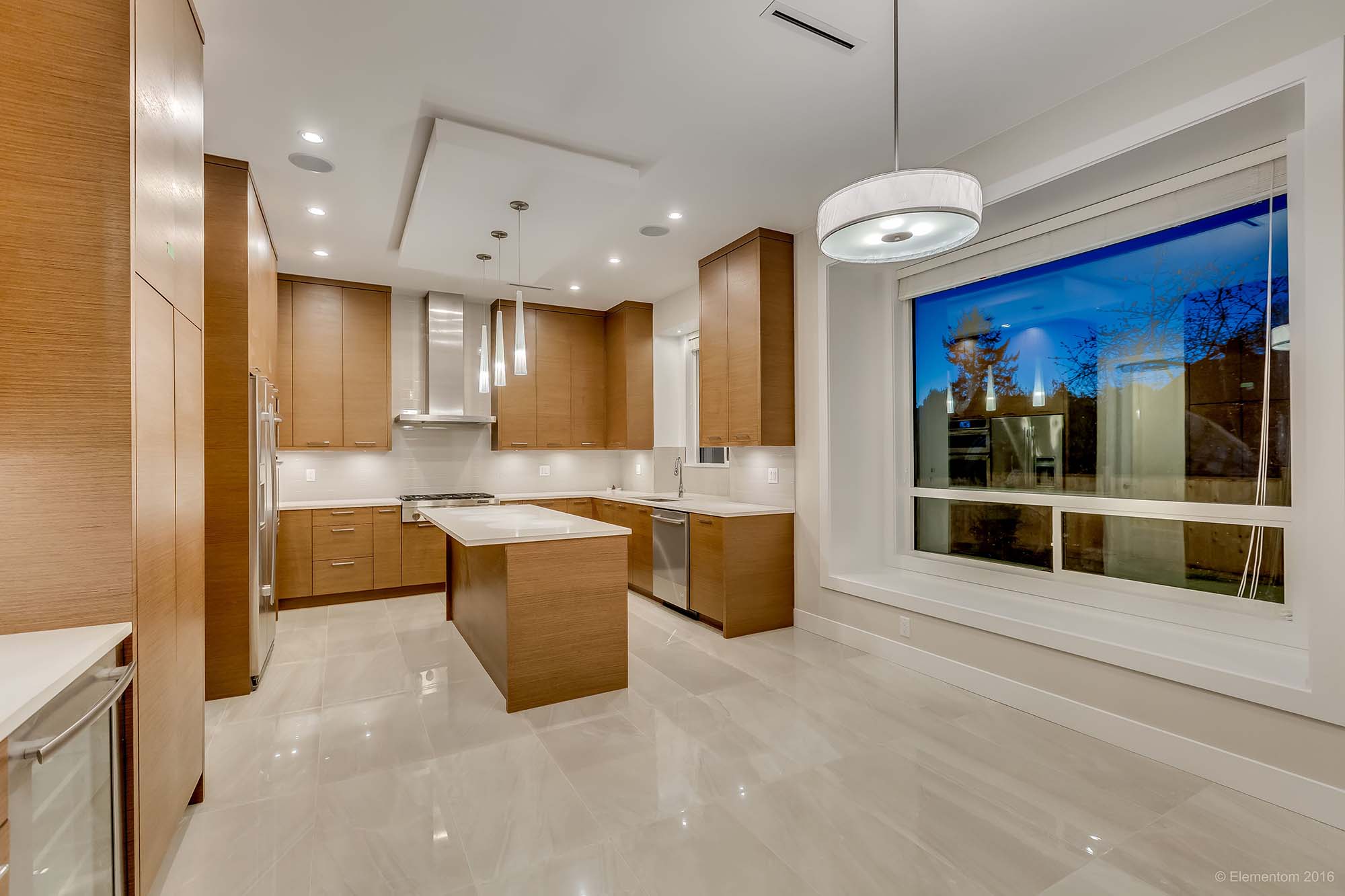 Modern kitchen with wood cabinetry, center island, and large window in a Greater Vancouver home