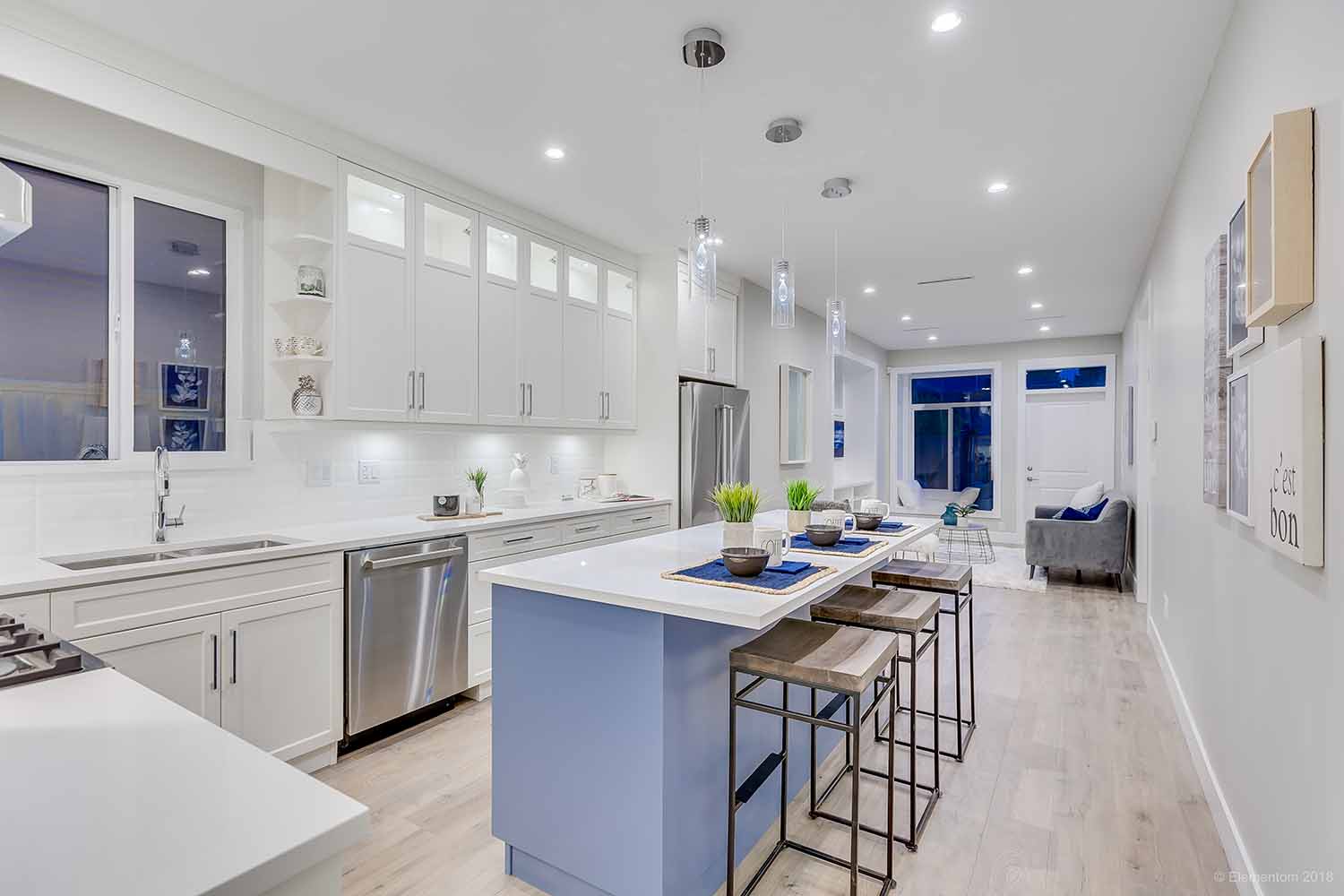 Modern white kitchen with large island, bar seating and open living area in a Vancouver home