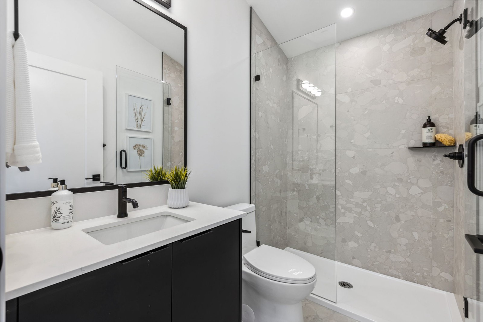 Vancouver bathroom with black vanity, walk in shower, and terrazzo tile