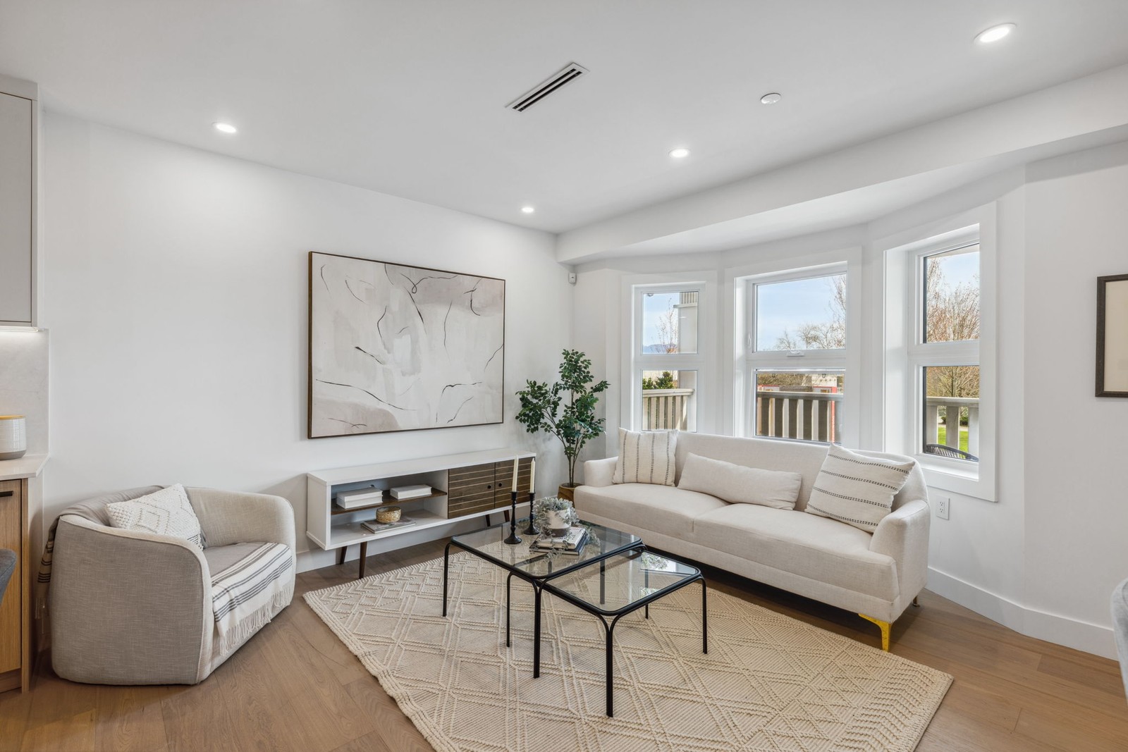 Vancouver living room with beige sofa, gray armchair, and large bay window Vancouver living room with beige sofa, gray armchair, and large bay window